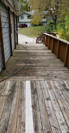 A weathered wooden deck with a bike and houses in the background. A hose runs across the deck.