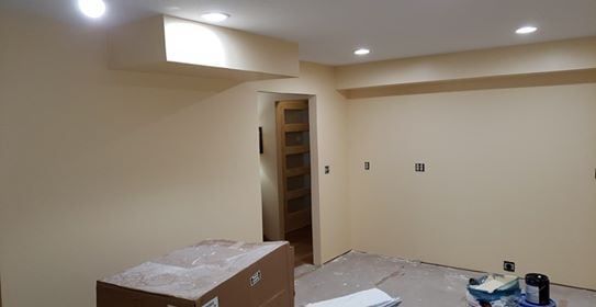 Cream-colored interior room under construction, with doorway, box, and recessed lighting.