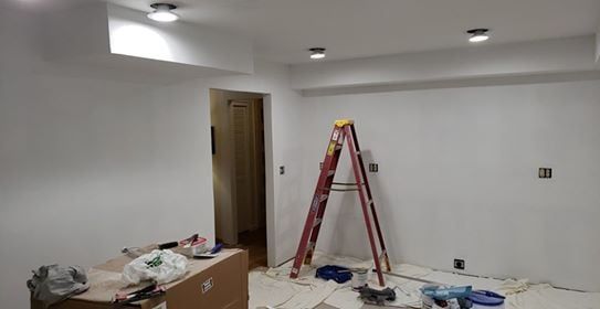 Room being renovated with ladder, tools, and newly painted white walls.