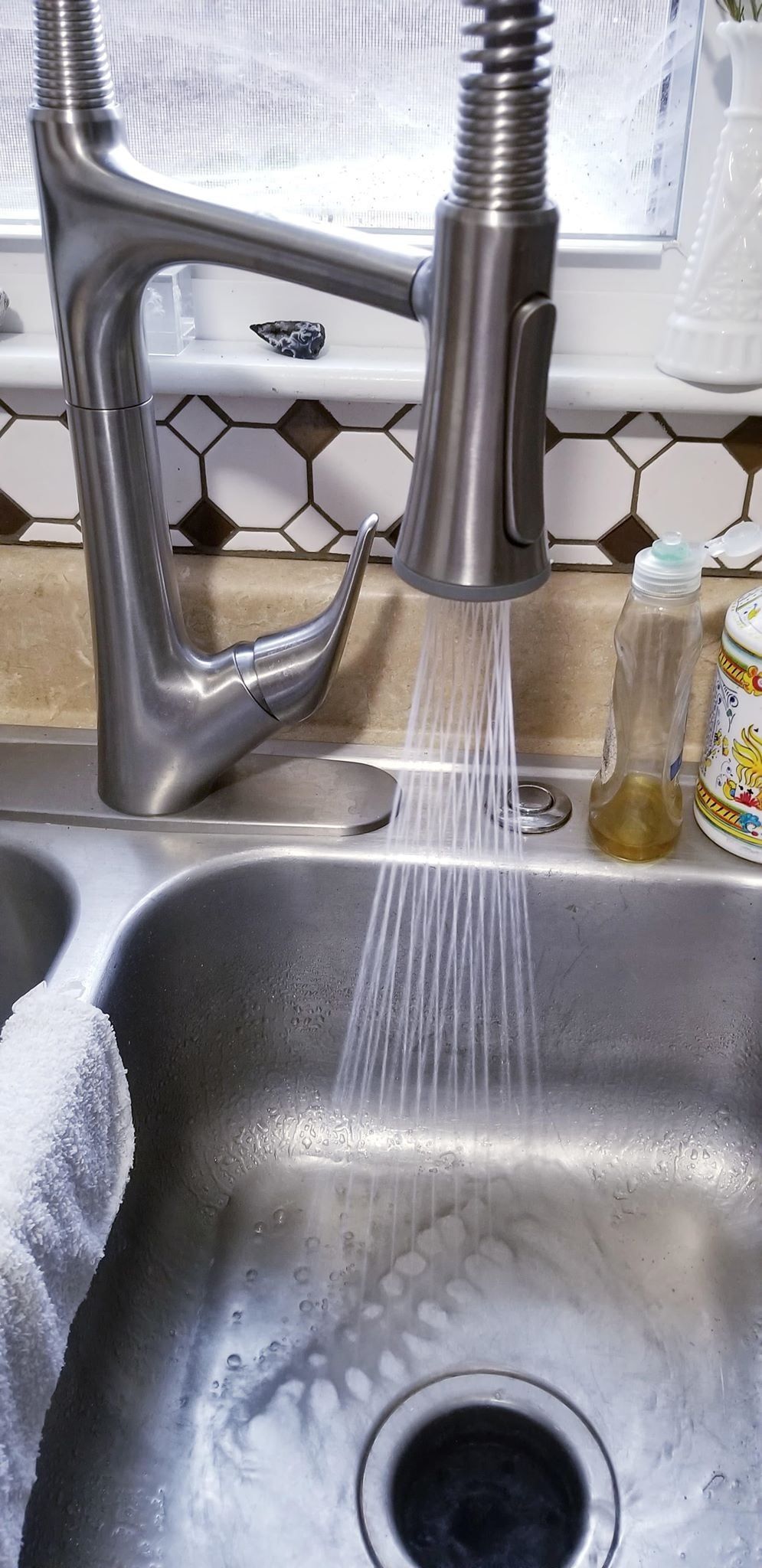 Kitchen sink faucet with water running into the stainless steel sink.
