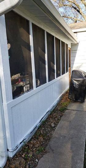 White screened porch with light-colored siding, a concrete walkway, and dry leaves along the bottom edge.