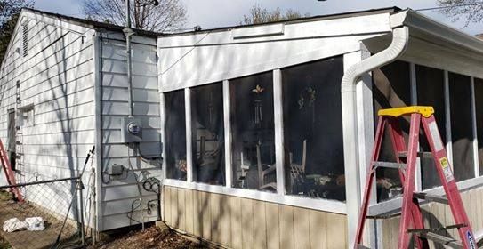 White house with a screened porch; a red ladder stands by the porch.