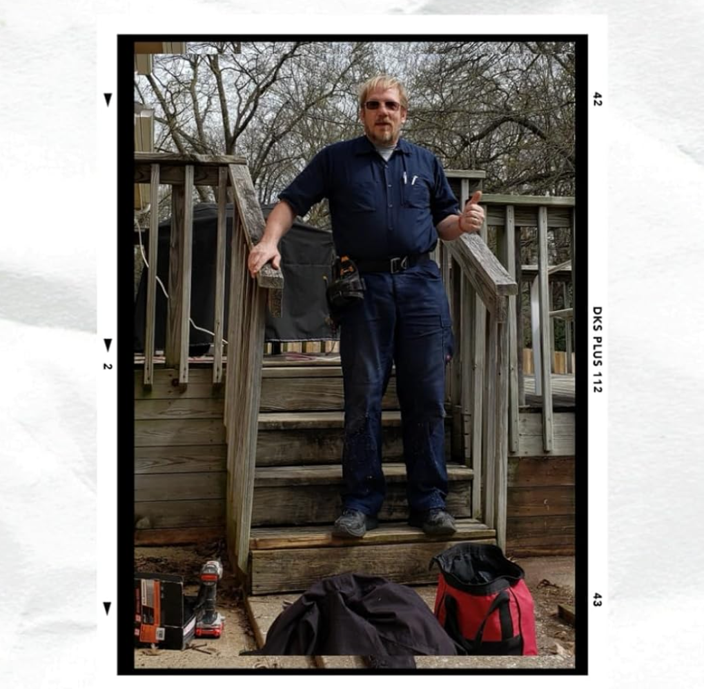 Man in blue work clothes on wooden steps, giving a thumbs-up. Tools and bags are at the bottom.