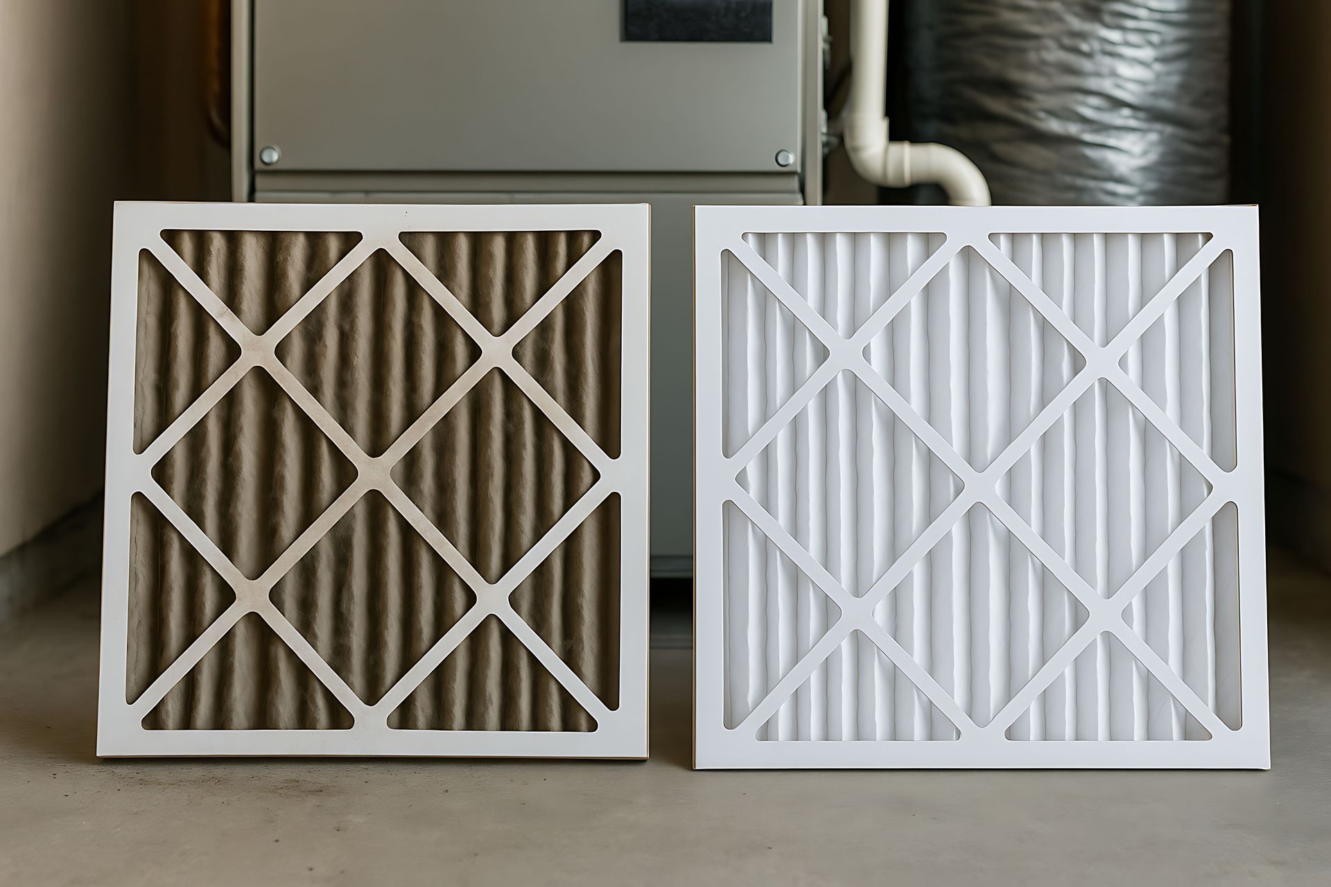 Two air filters: one dirty, brown; one new, white, in front of a furnace.