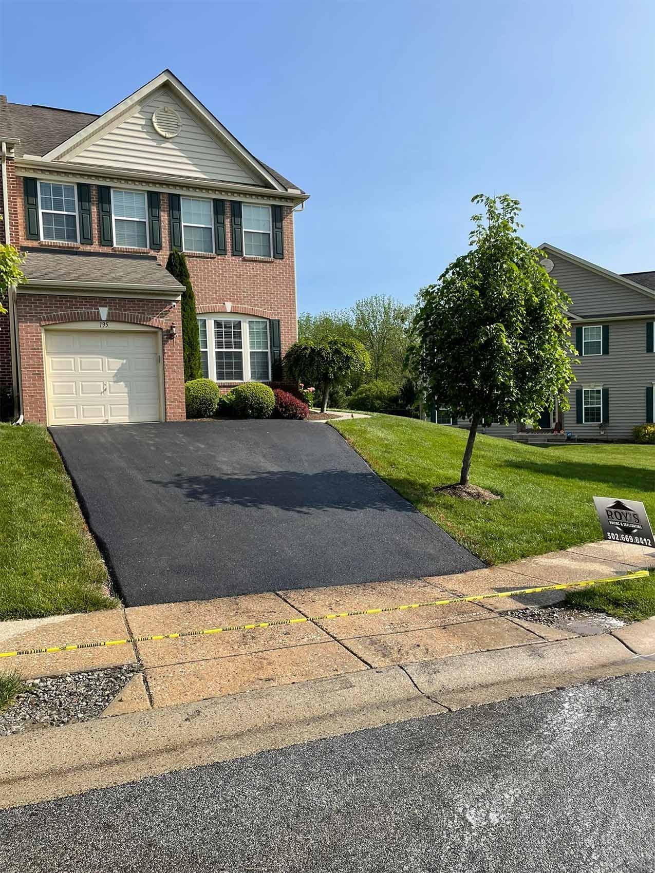 A brick house with a black driveway and a white garage door