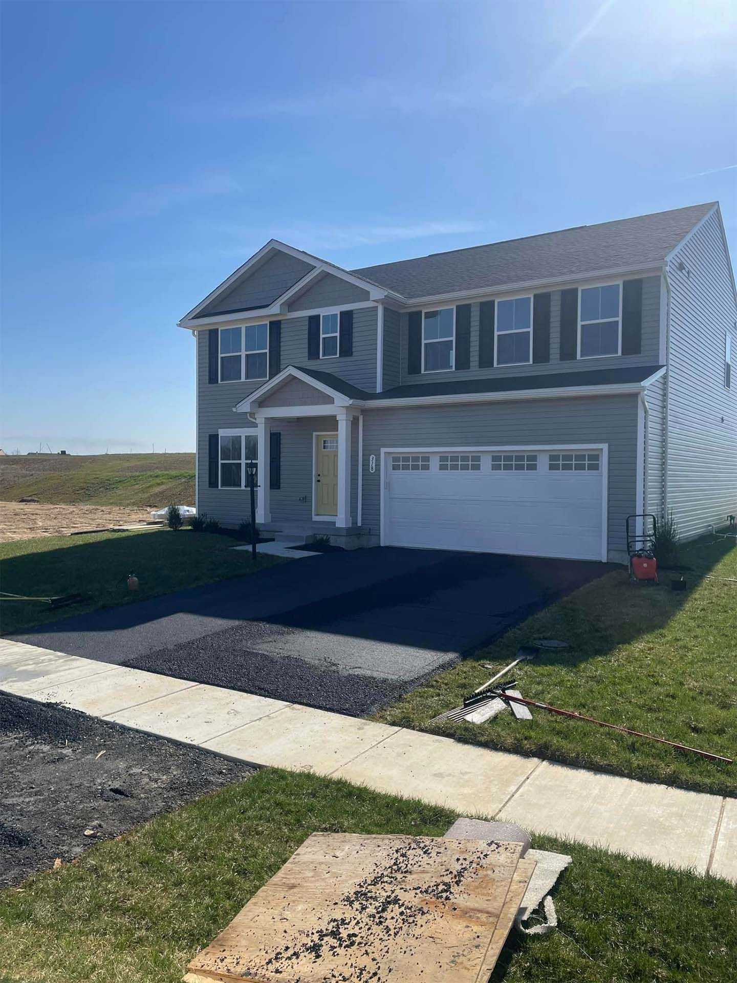 A large house with a white garage door surrounded by a lush green field