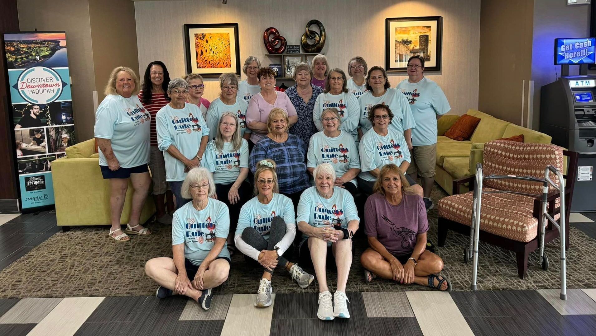 Group of women in matching t-shirts pose together indoors.