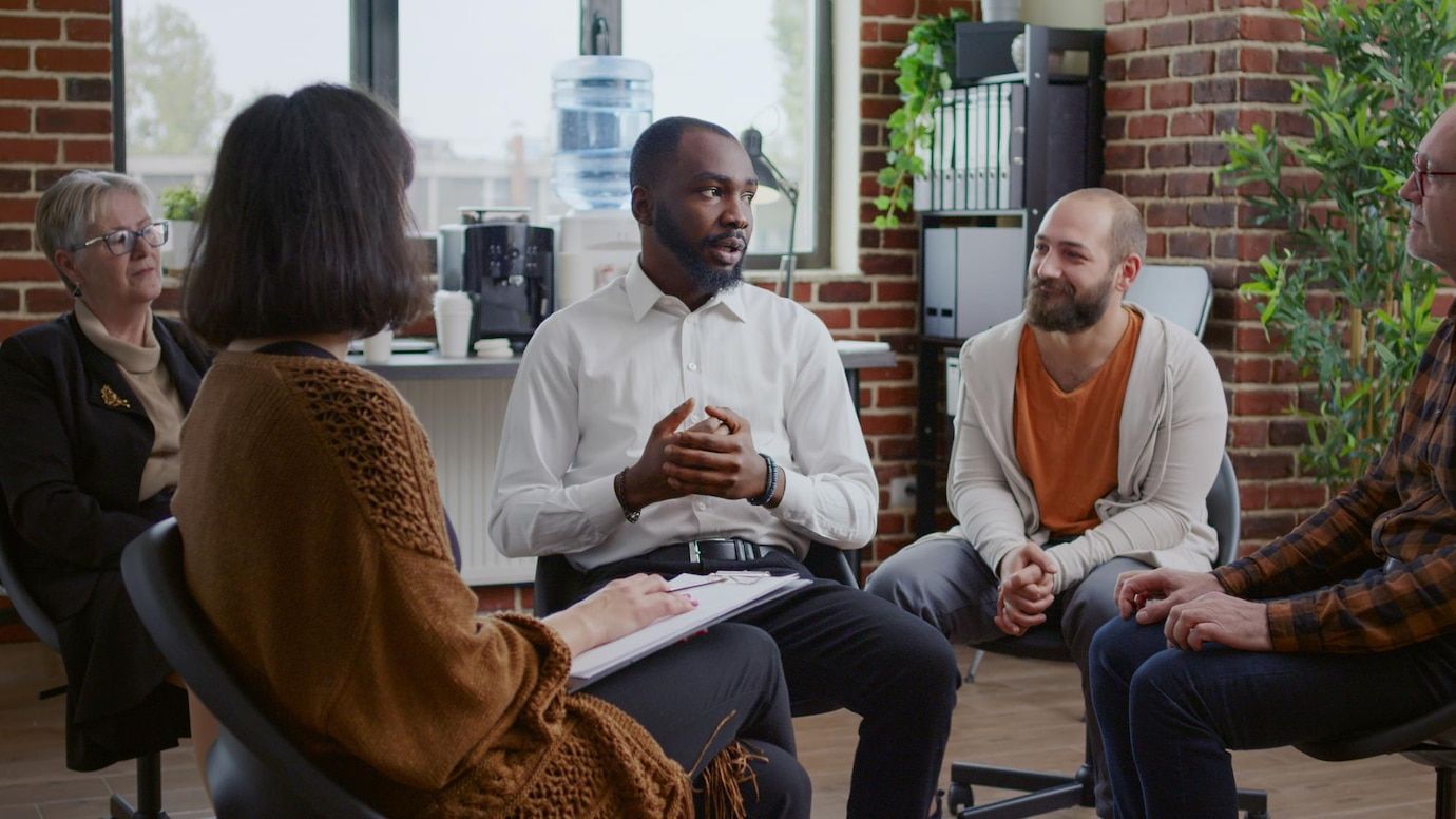 A group of people are sitting in a circle talking to each other.