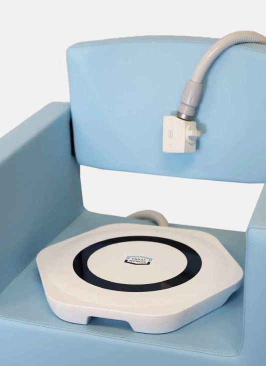 Blue chair with a white, hexagonal device on the seat, a hose connected to the device and the chair back.