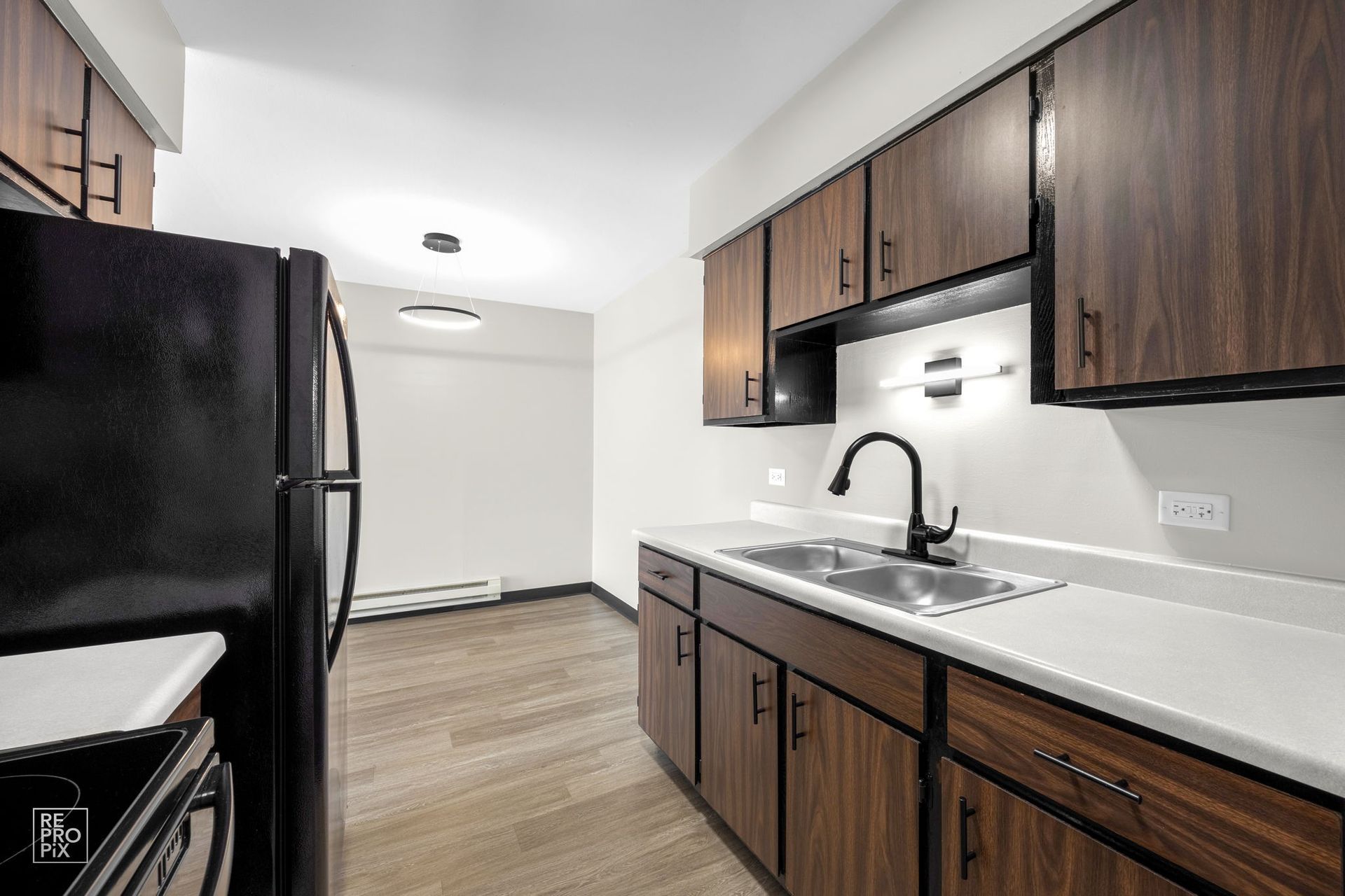 Kitchen with dark brown cabinets, black appliances, and a stainless steel sink.