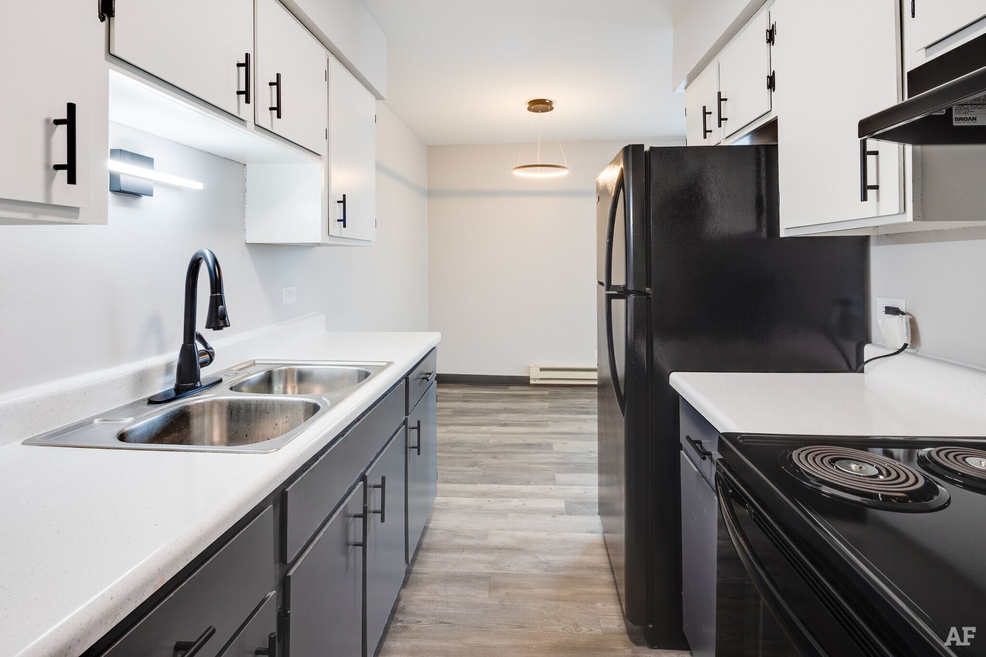 Modern kitchen with white and gray cabinets, black appliances, and gray flooring.