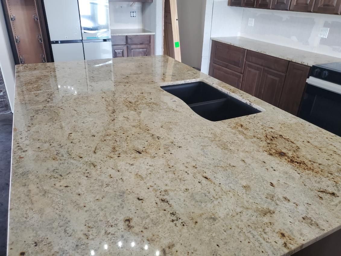 Granite kitchen countertop with a black sink and brown cabinets.