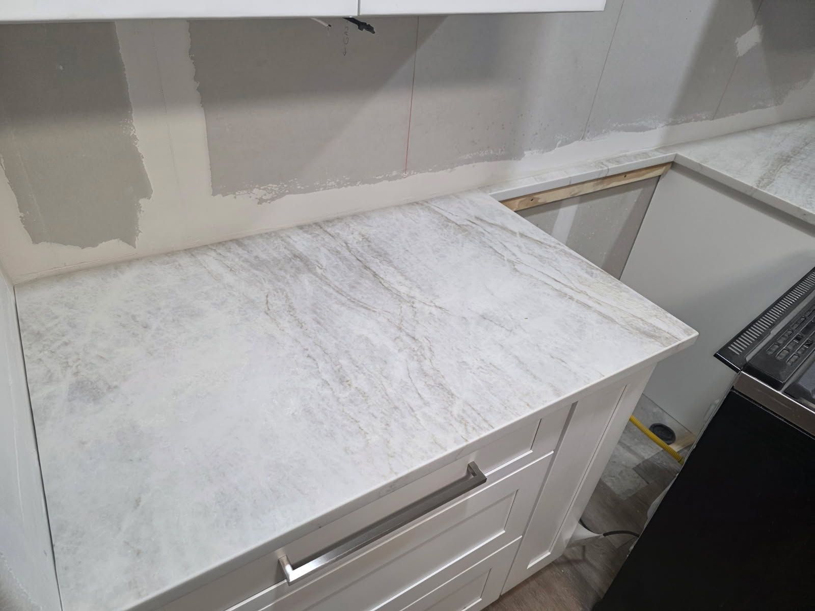 White kitchen countertop with cabinets, under construction.