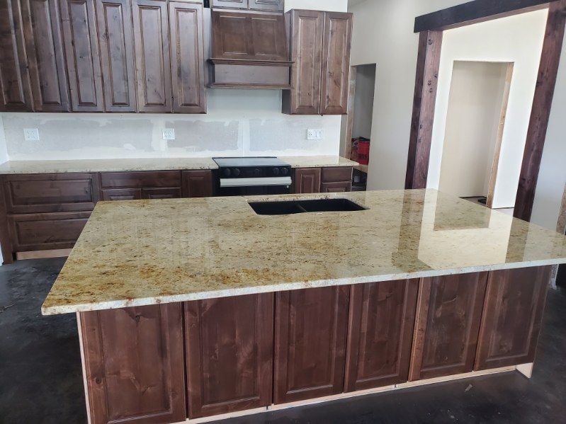 Kitchen with dark brown cabinets, a granite countertop island, and a cooktop.