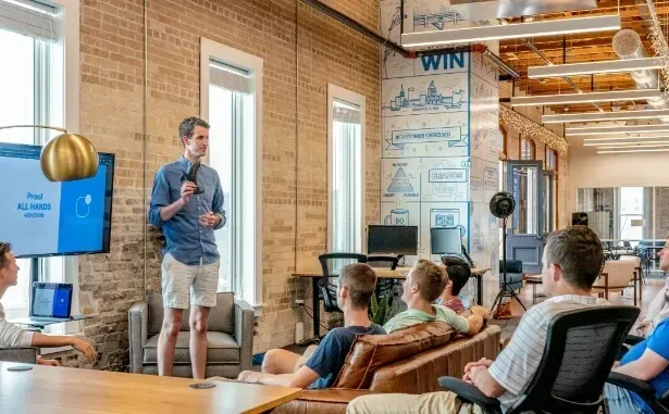 Young entrepreneur presenting a business plan to a small team in a modern, casual office space.
