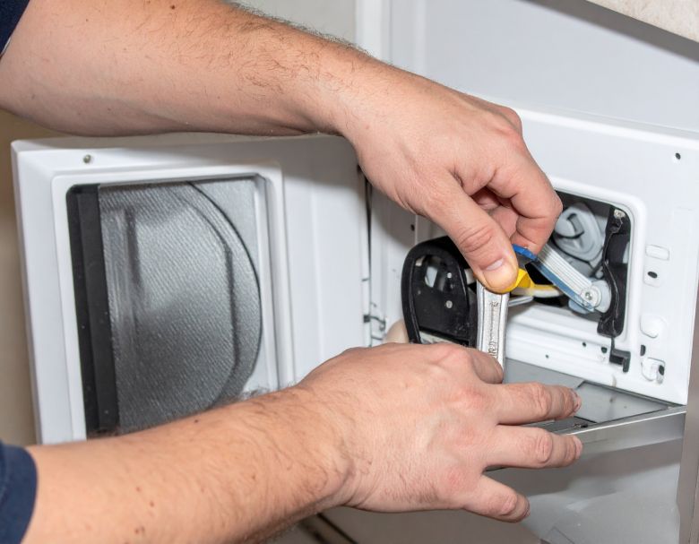 Person cleaning the lint filter of a white washing machine.