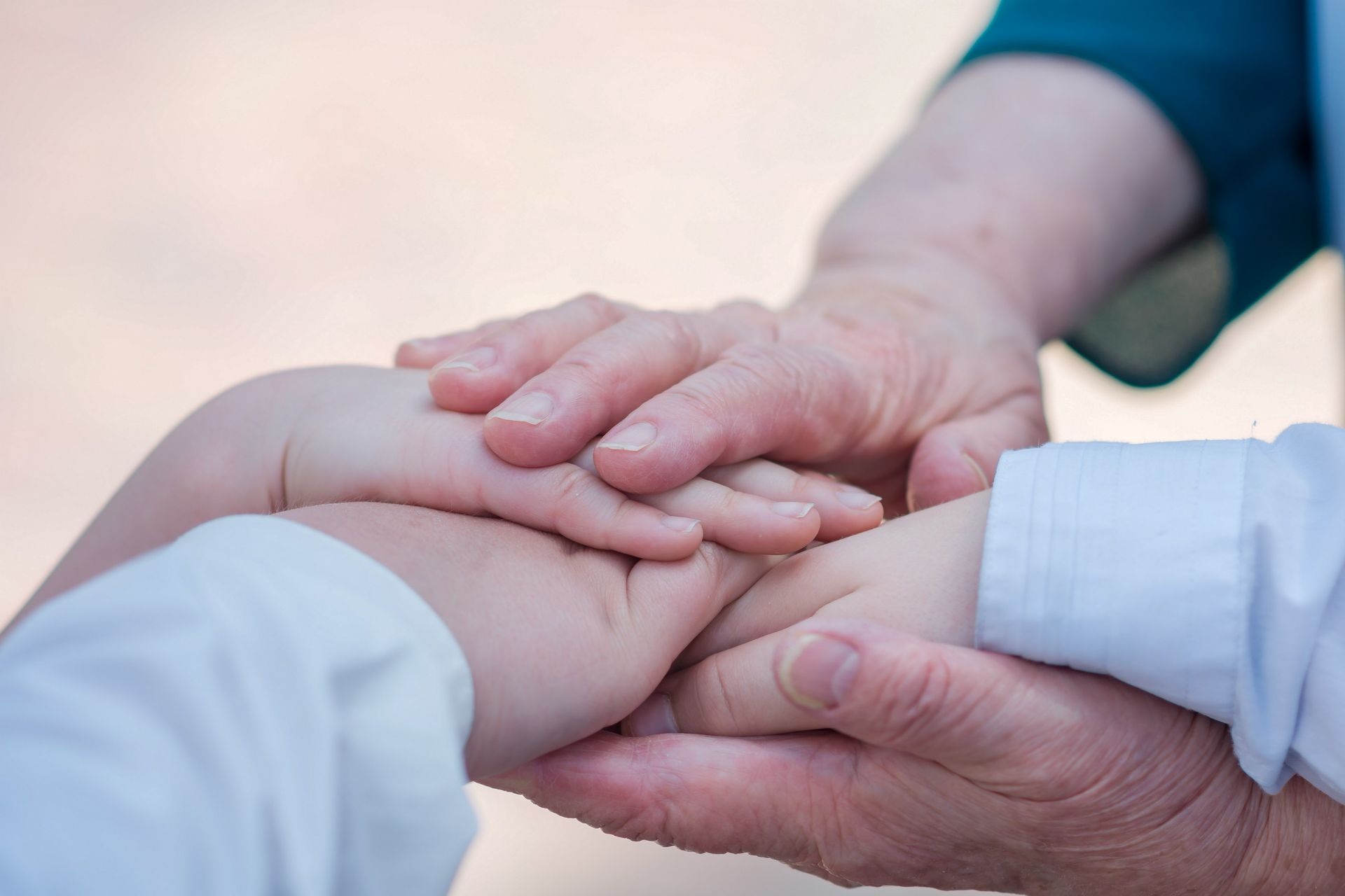 Hands stacked together, adult hands on child's hands, forming a supportive gesture.