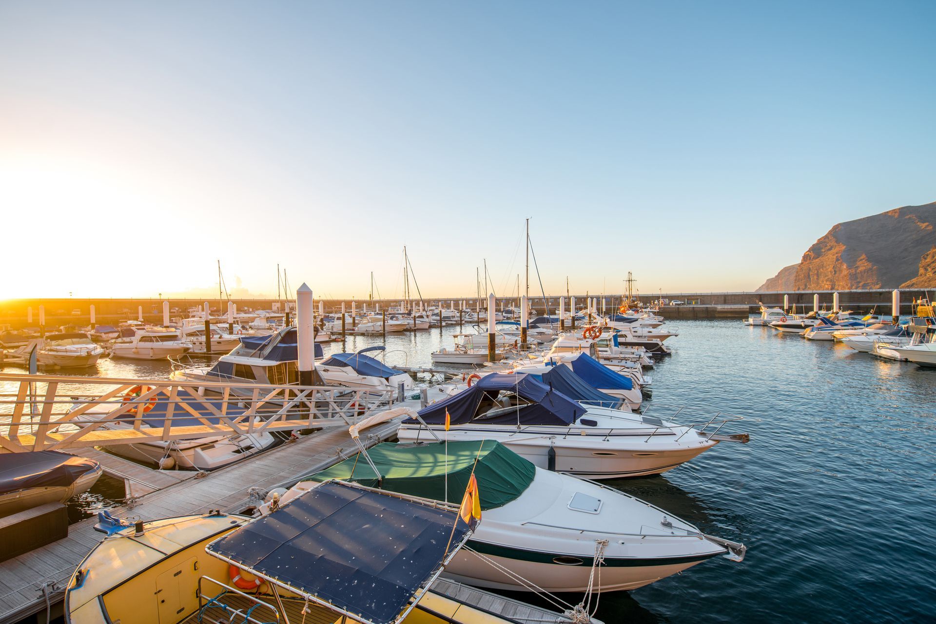 Boats docked in a marina, lit by the setting sun.