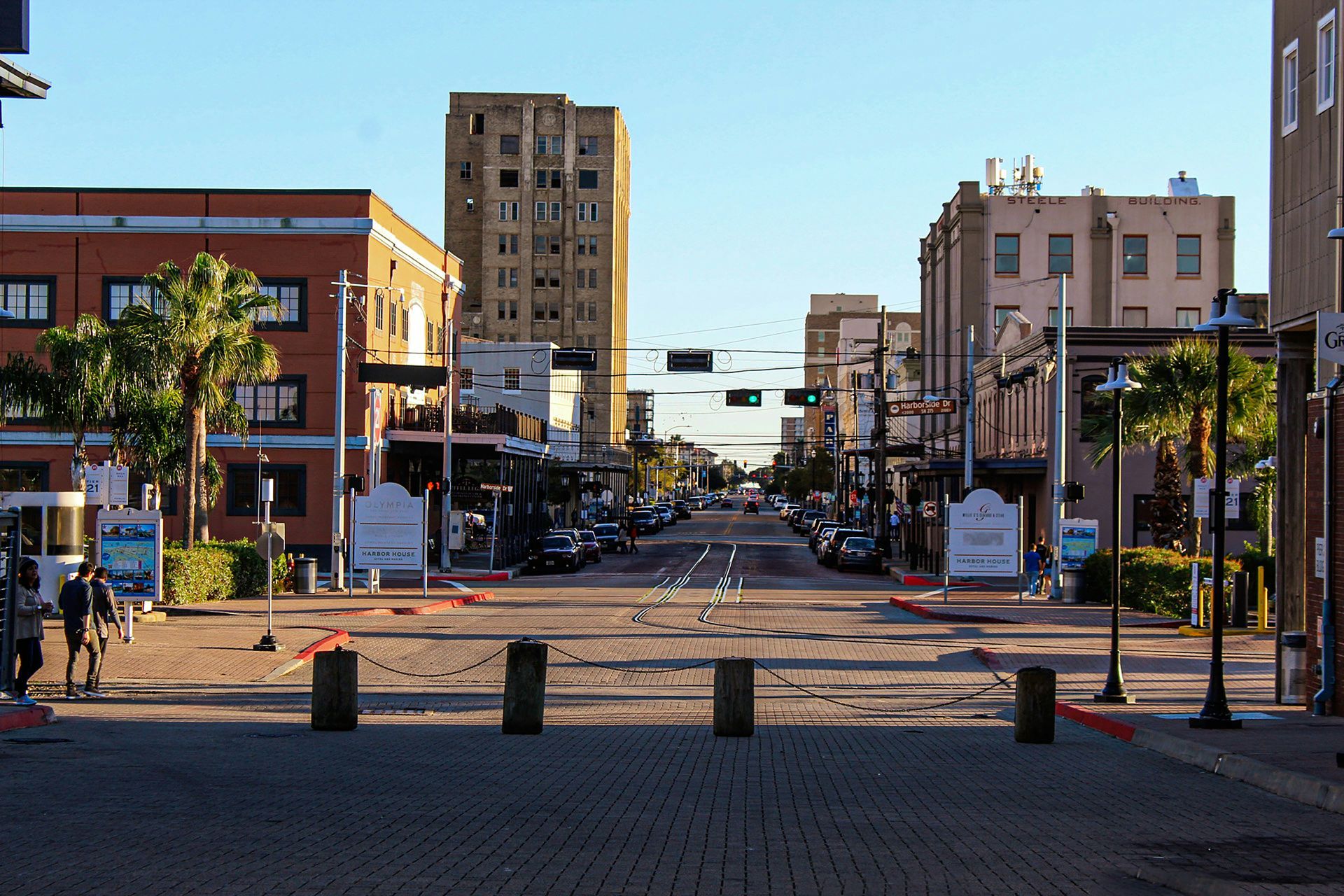 Street scene with brick pavement, buildings, and cars under a clear sky.