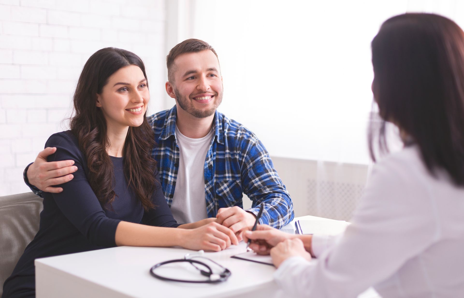 Couple smiling, meeting with a medical professional at a table.