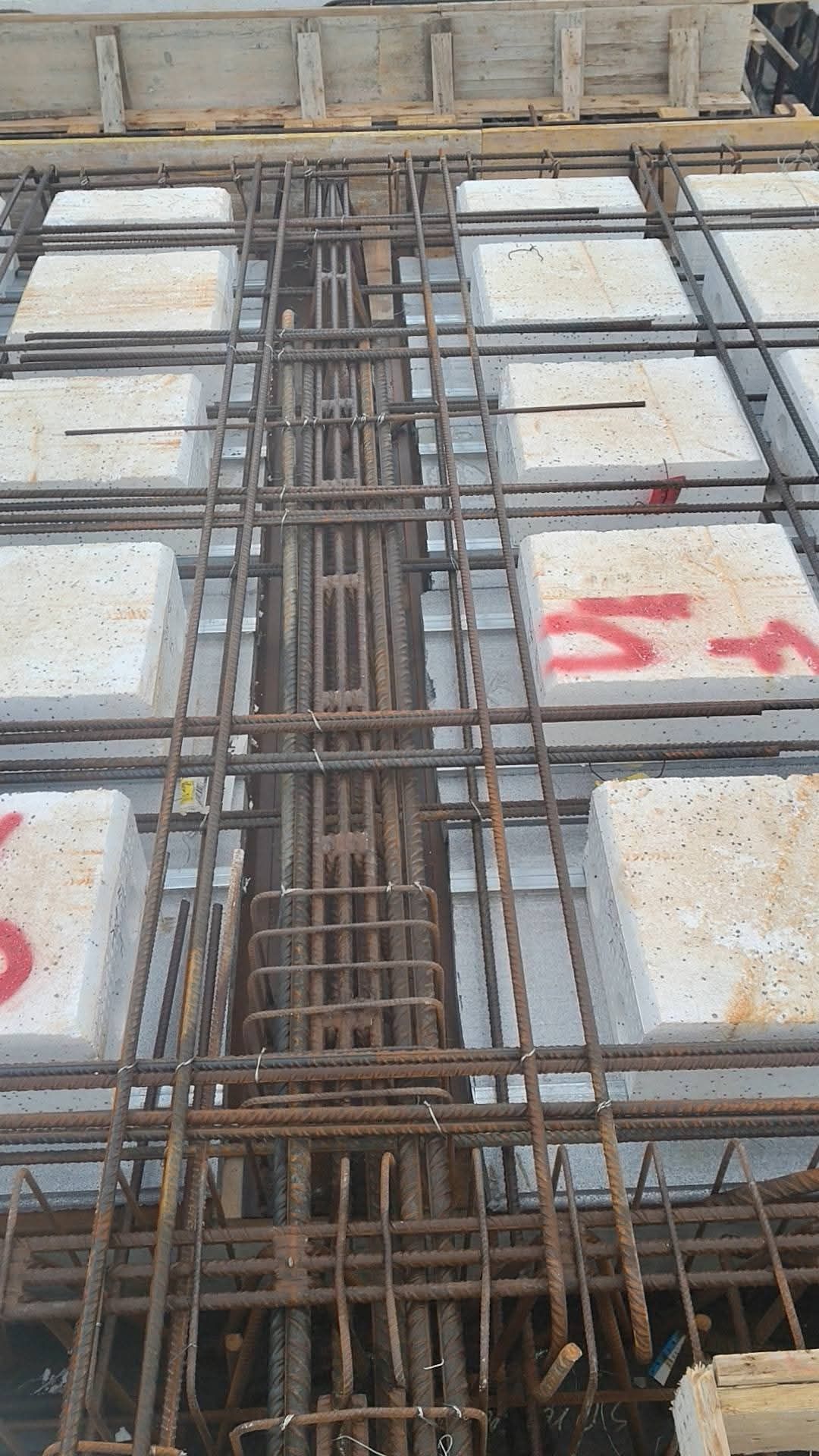 Casseforme per lastre di cemento con griglia di armatura a vista e blocchi di schiuma bianca in un cantiere edile.