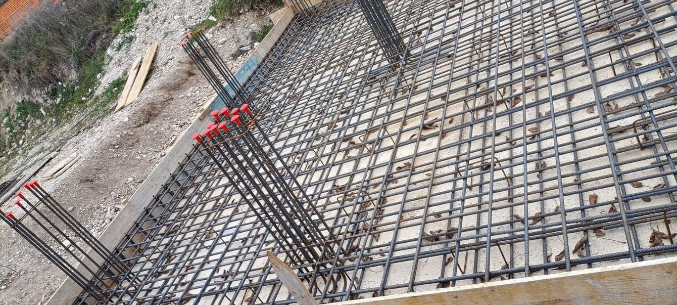 Rete di barre d'armatura per una fondazione in cemento armato in un cantiere, vista da un'angolazione diversa.