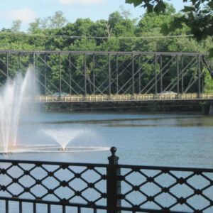 A bridge over a body of water with a fountain in the foreground