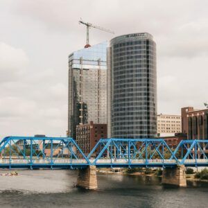 A blue bridge over a river in a city with tall buildings in the background.