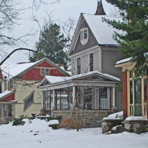A row of houses covered in snow with trees in the background