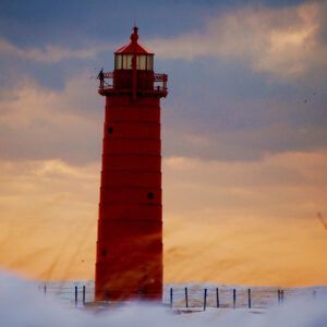 A red lighthouse is standing in the middle of a snowy field.