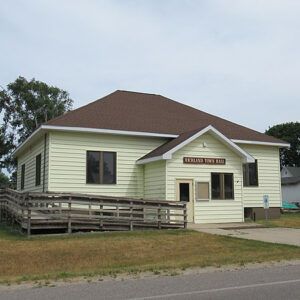 A small white house with a brown roof and a ramp