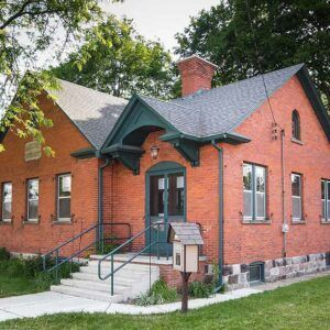 A red brick building with a green roof and a mailbox in front of it.