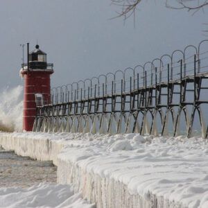 A lighthouse sits on top of a snow covered pier