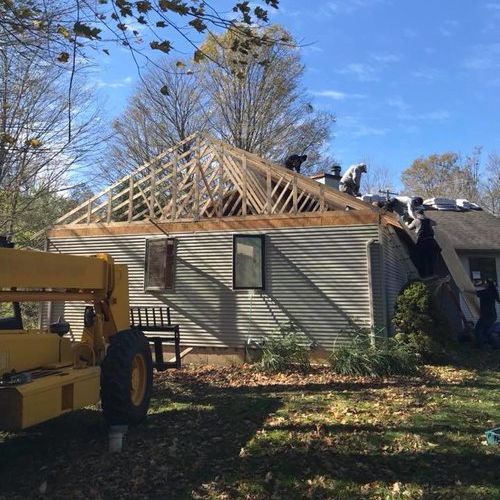 A yellow forklift is parked in front of a house under construction.