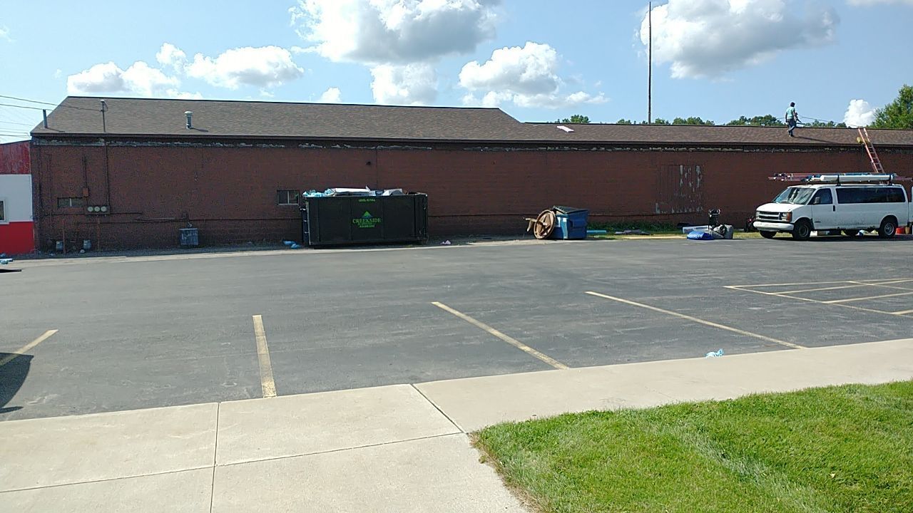 A white van is parked in a parking lot in front of a brick building