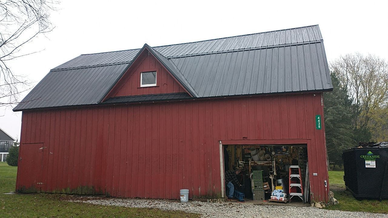 A red barn with a black roof and a garage door.