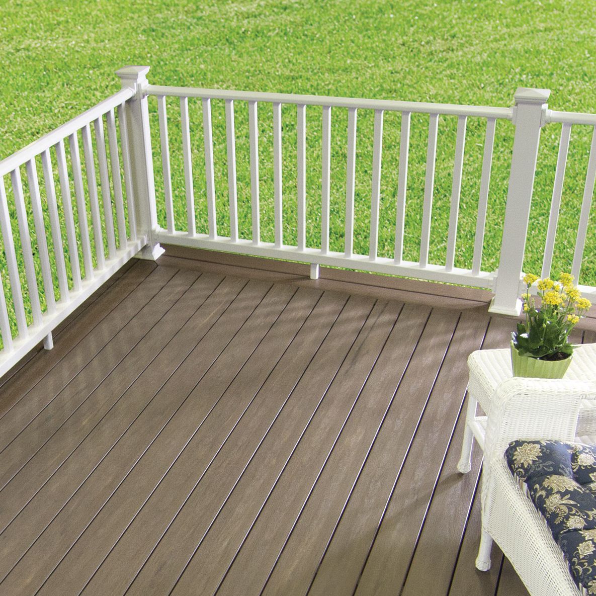 A wooden deck with a white railing and a wicker chair