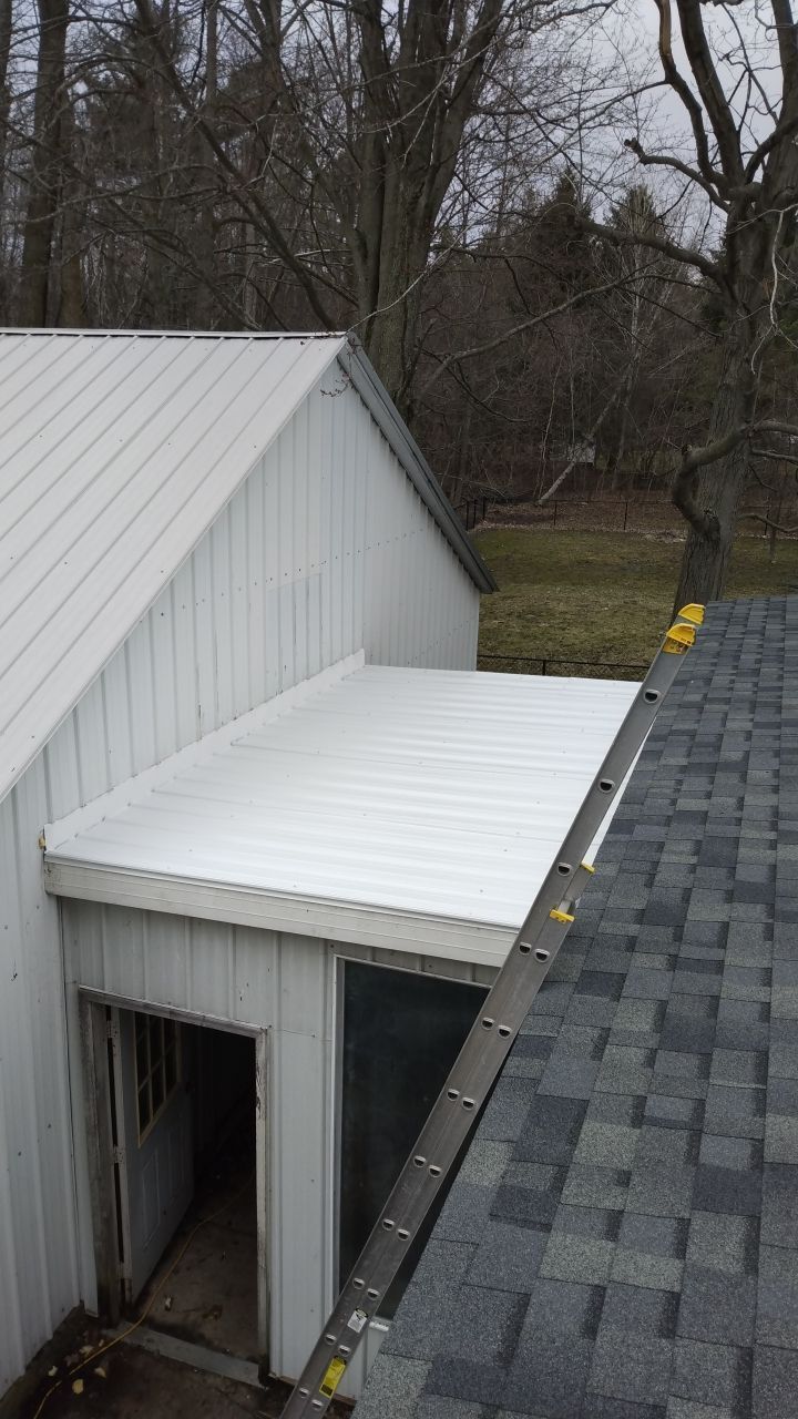 A white building with a roof that is covered in shingles.