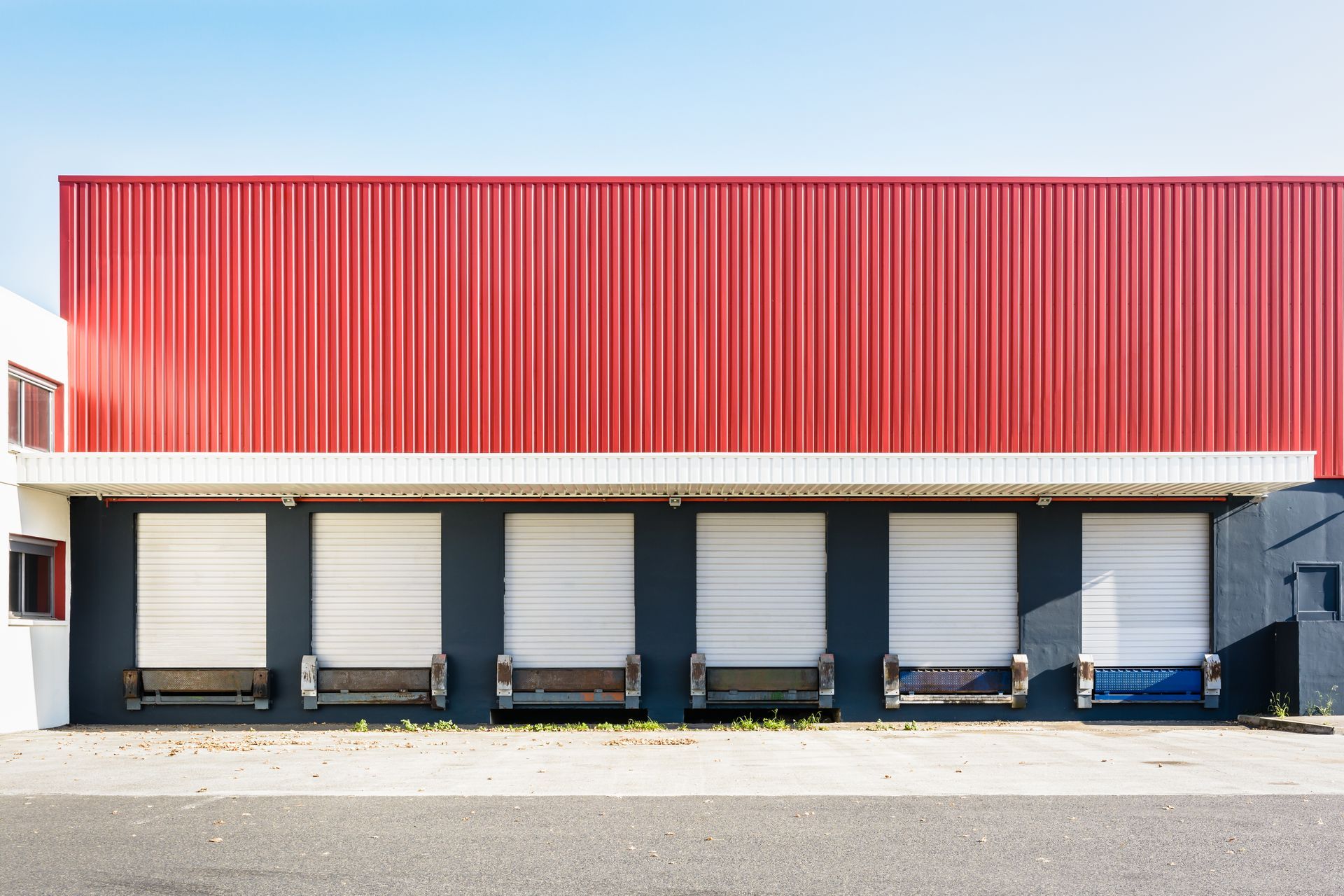 A warehouse with a red roof and white doors.