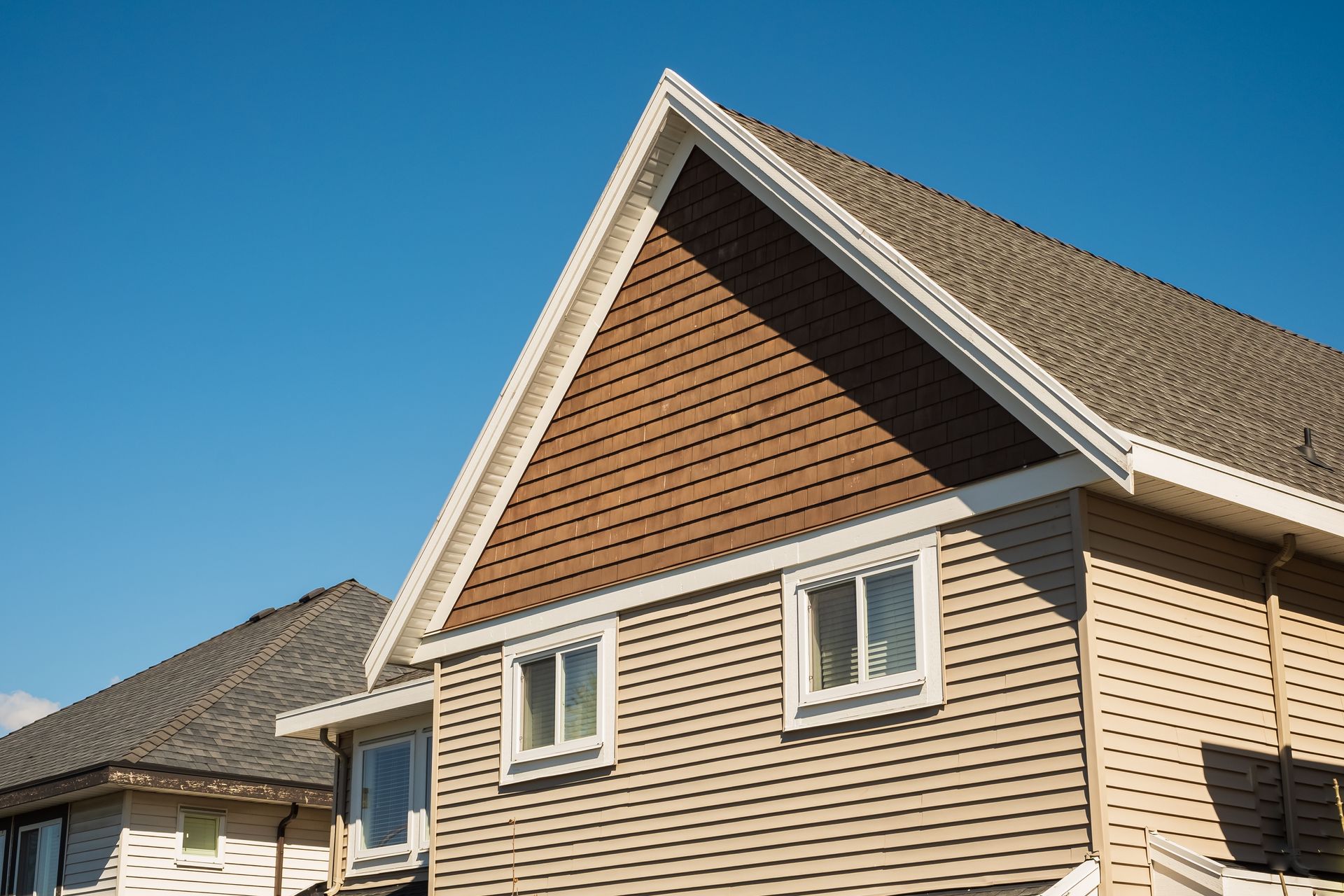 A house with a triangle shaped roof and a brown siding