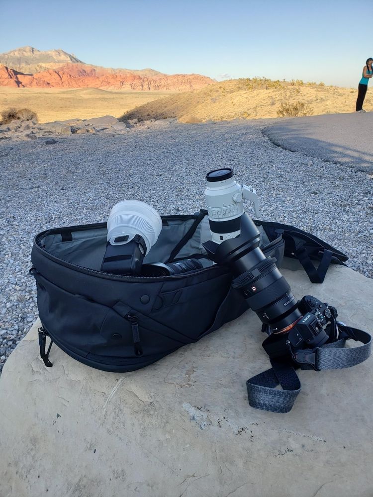 A camera is sitting on a rock next to a bag.