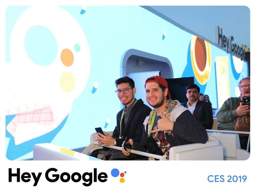 A group of people are sitting in front of a screen that says hey google