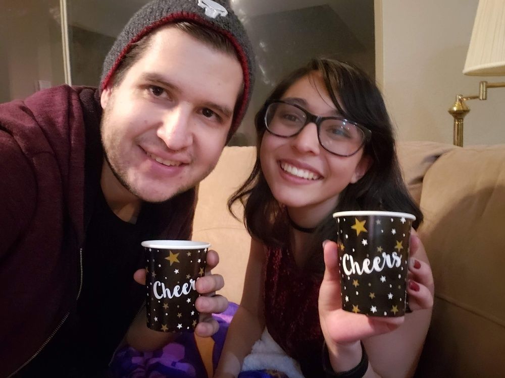 A man and a woman are holding cups that say cheers