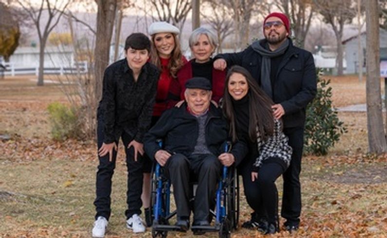 A family posing for a picture with a man in a wheelchair.