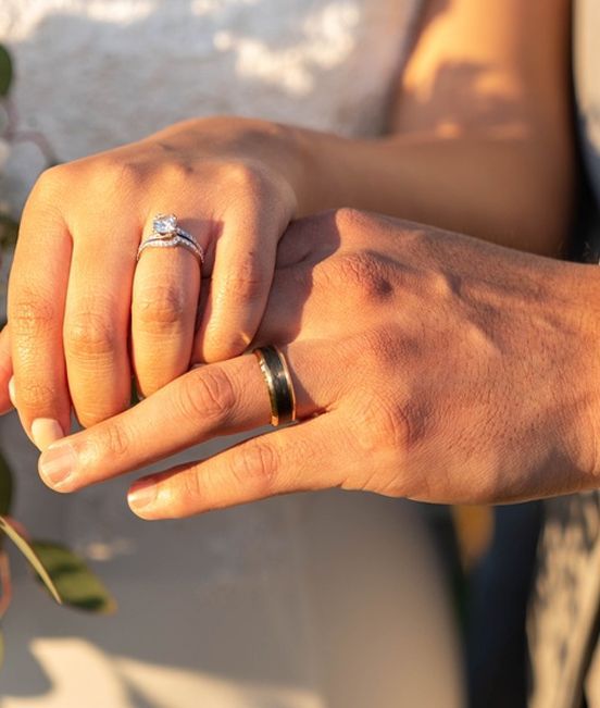 A man is putting a wedding ring on a woman 's finger.