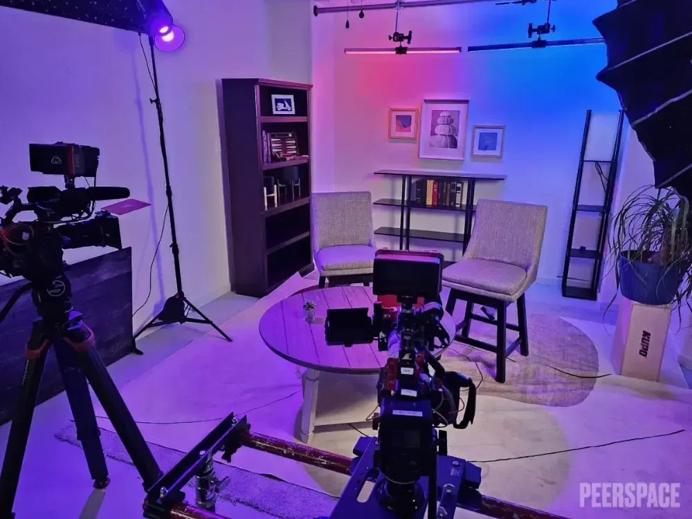 A camera is sitting on a tripod in a room with purple lights.