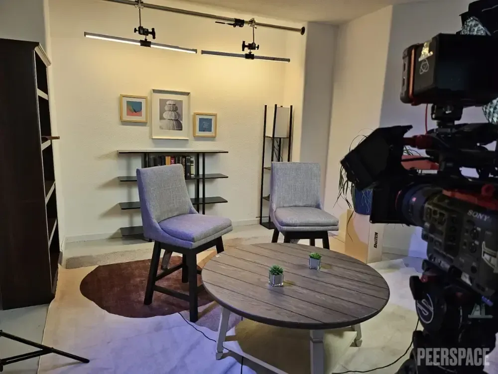 A room with a table and chairs and a camera that says peerspace