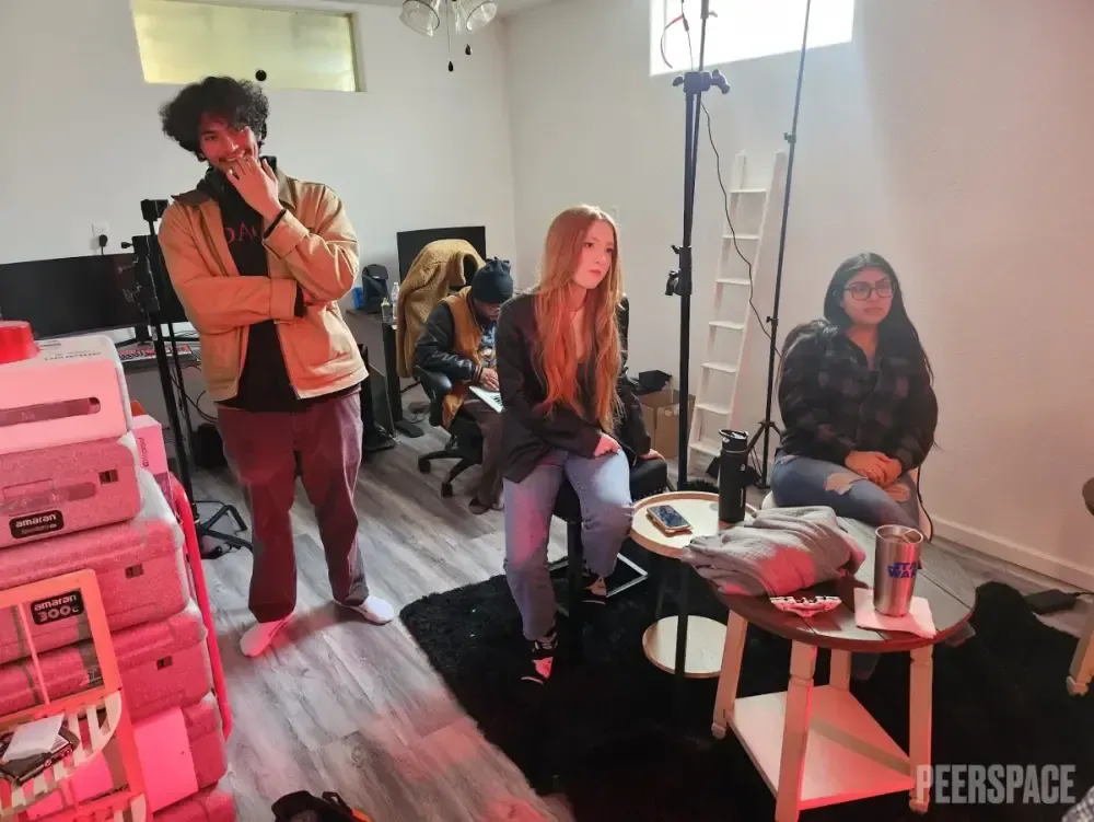A group of people are sitting around a table in a living room.