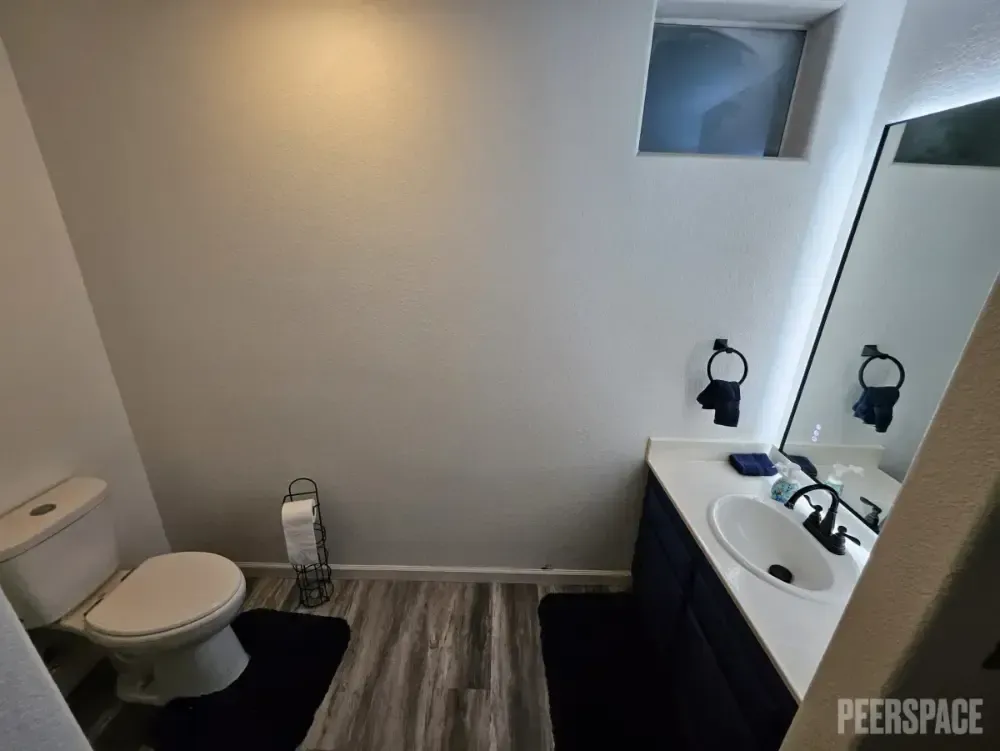 A bathroom with a toilet , sink and mirror.