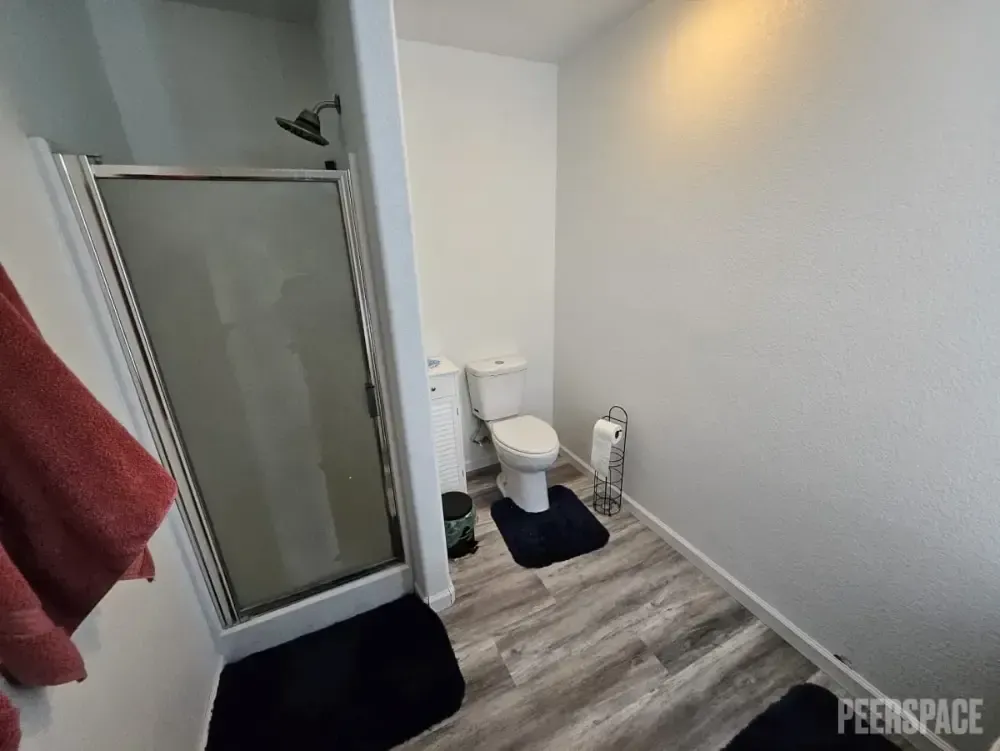 A bathroom with a toilet , shower , and towel.